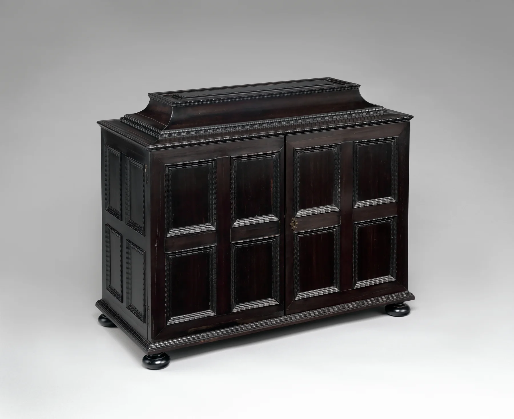 A 17th-century collector's cabinet veneered in ebony with paneled doors and turned bun feet, attributed to Herman Doomer